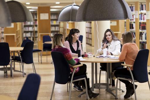 Four students at a round table in a library
