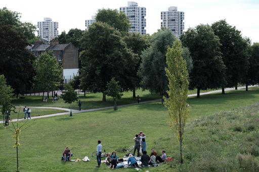 En grupp sitter i en park, med höghus i bakgrunden