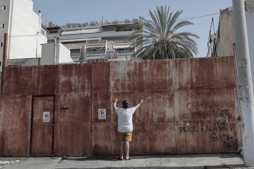 En person står mot en mur i en stad med palmer