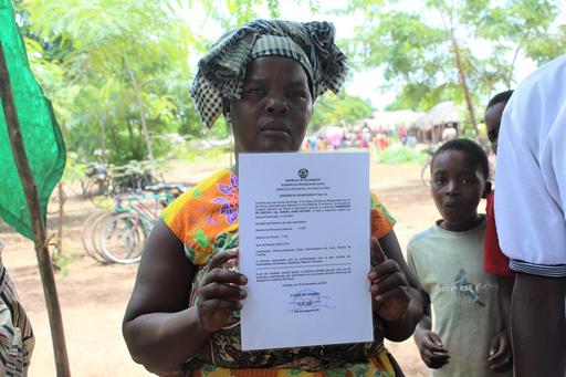 Foto på kvinna i norra Mocambique visar upp certifikat för sitt landområde.