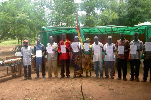 Foto på representanter för lokalsamhällen som visar upp certifikaten för sina landområden