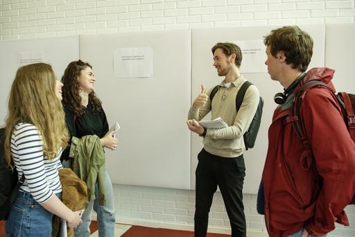 Fyra personer samtalar framför en vit vägg