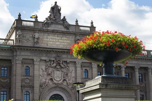Riksdagshusets fasad med en blomma i förgrunden