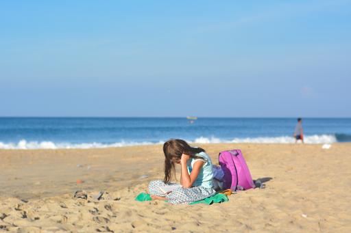 Barn läser på strand. 