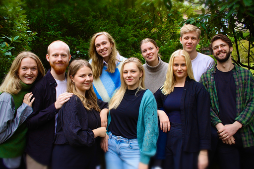 En grupp personer uppställda på rad , omringade av träd och buskar