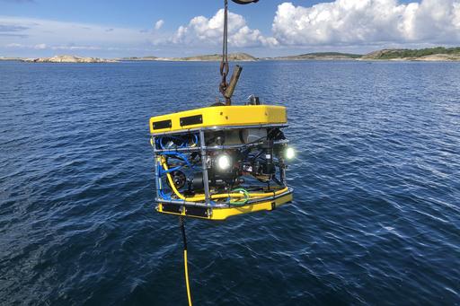 A yellow remotely operated vehicle is being deployed in the sea