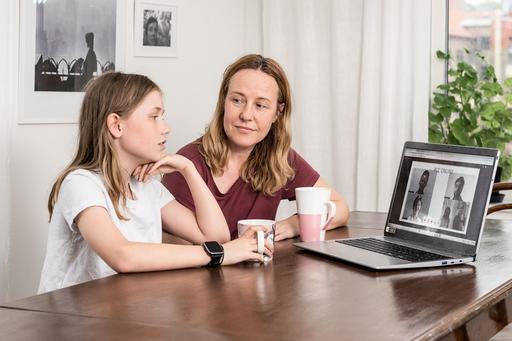 Personcentrerat digitalt vårdmöte med mamma och barn hemma vid köksbordet och flera personer på datorskärm.