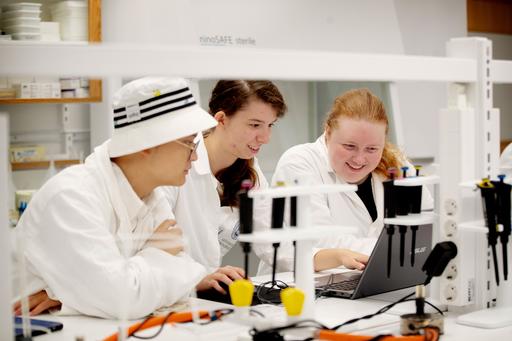 Students in white lab coats in a lab