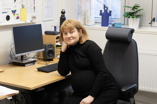 kvinna sitter vid kontorsskrivbord och tittar mot kameran
