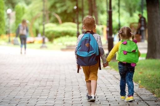 Barn hand i hand på promenad i en grönskande park