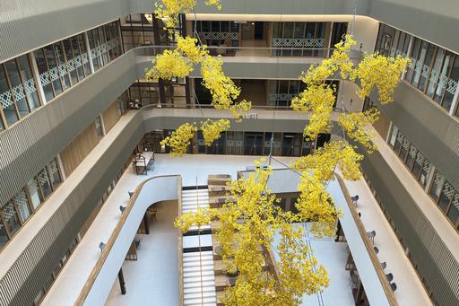 A tree with yellow leaves hanging upside down in a building with staircases on both sides.