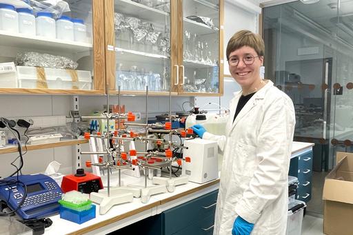 En forskare i vit labbrock står i ett laboratorium med prover.