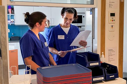 två studenter i blå vårdkläder i kök på vårdavdelning