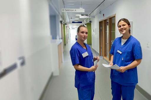 två kvinnliga vårdpersonal i sjukhuskorridor