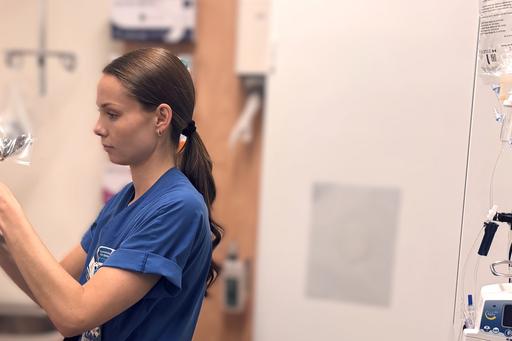 Kvinna i vårdkläder förbereder ett dropp