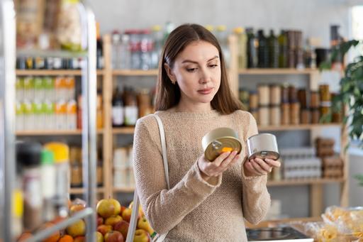 Kvinna jämför två konservburkar