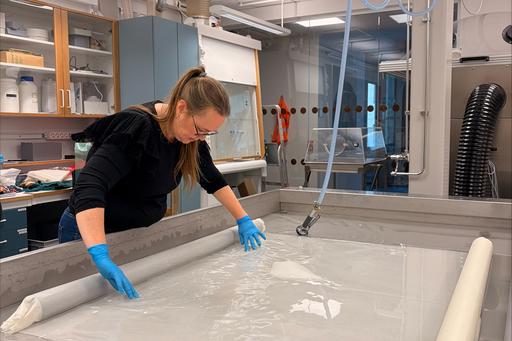 Person rengör textilt material i ett tvättbord, foto.