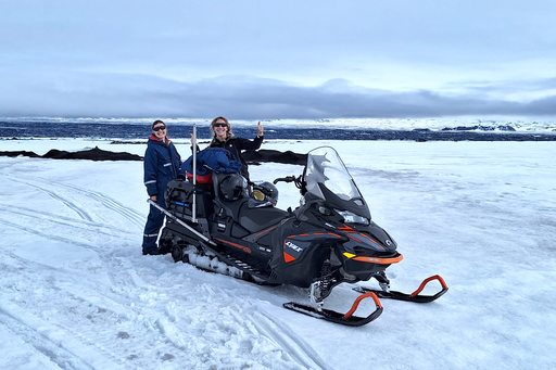 Two researchers on a snow scooter on a glacier.