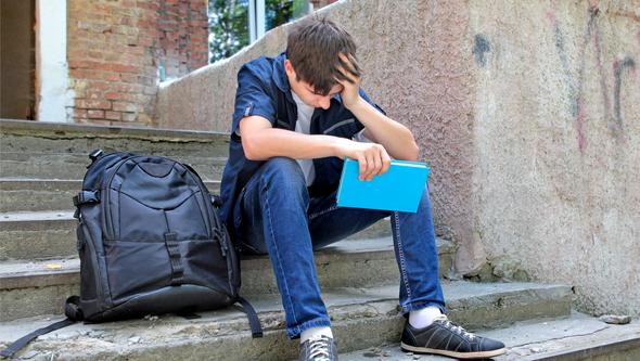 Sad school boy sitting on the step