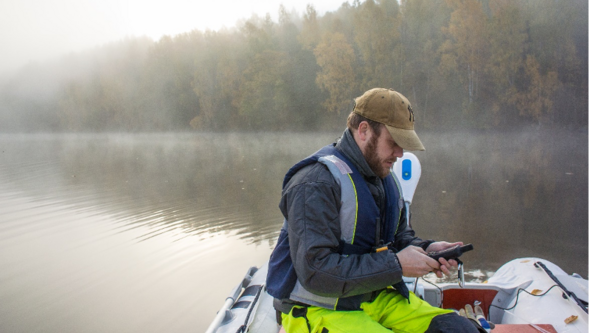 En man sitter i en båt och utför mätningar.