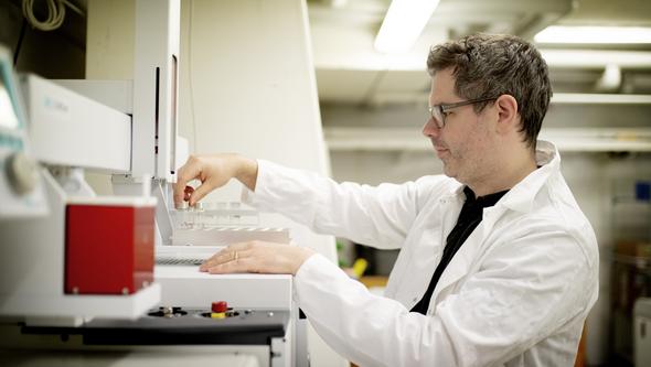 En man arbetar iförd vit labb-rock i ett forskningslaboratorium