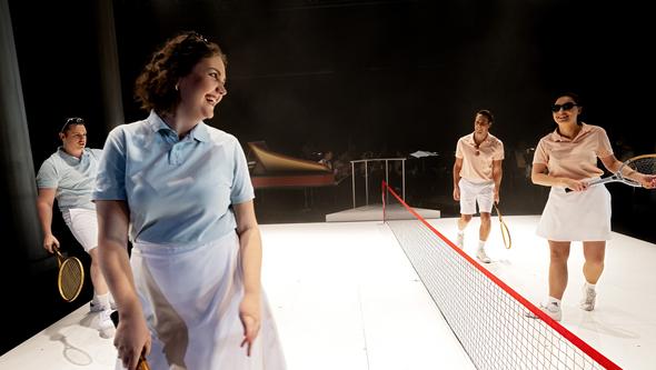 Fyra personer spelar tennis på scen