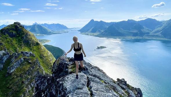 En kvinna står högt upp på en klippa och ser ut över havet. 