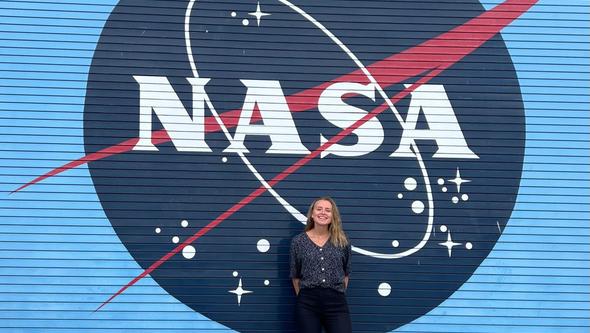 En kvinna står framför en skylt där det står  "NASA".
