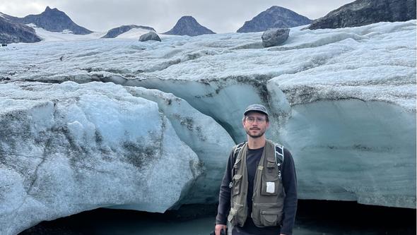 En man står framför en glaciär.