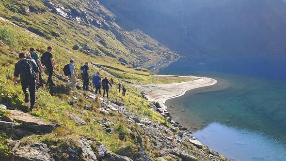 En grupp studenter vandrar i svenska fjällen med vacker utsikt. 