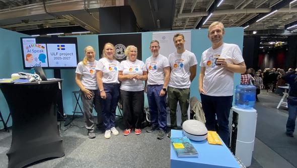 Projektgruppen för AI Speak poserar på Bok- och biblioteksmässan i t-shirtar med projektets färgglada logga.