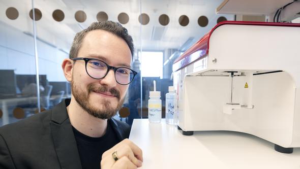 A man by a white machine in a laboratory.
