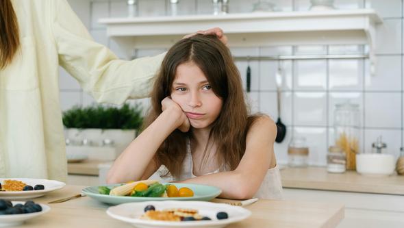 Young girl eating and unhappy