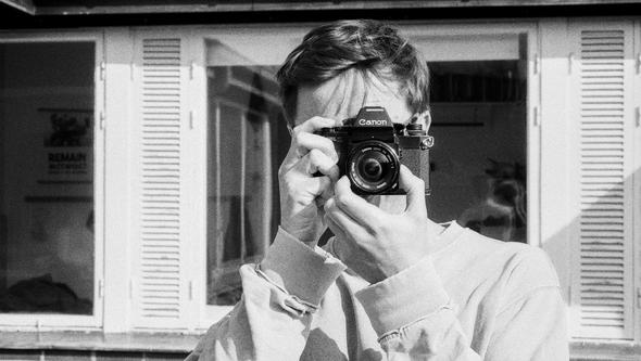 Bland and white image of a man with a camera