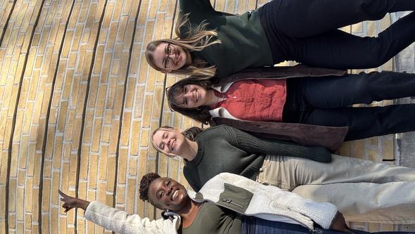 Izabella standing against a yellow brick wall with some friends.