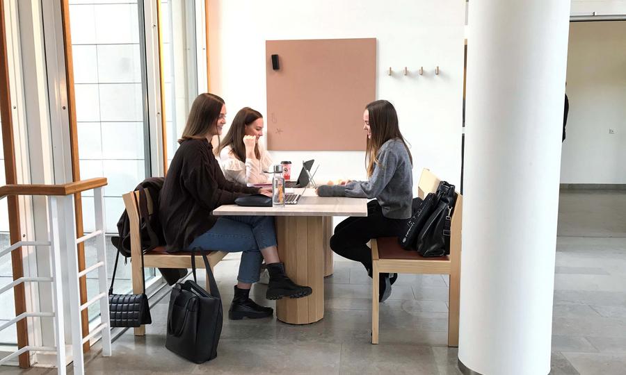 Tre kvinnliga studenter sitter runt ett bord