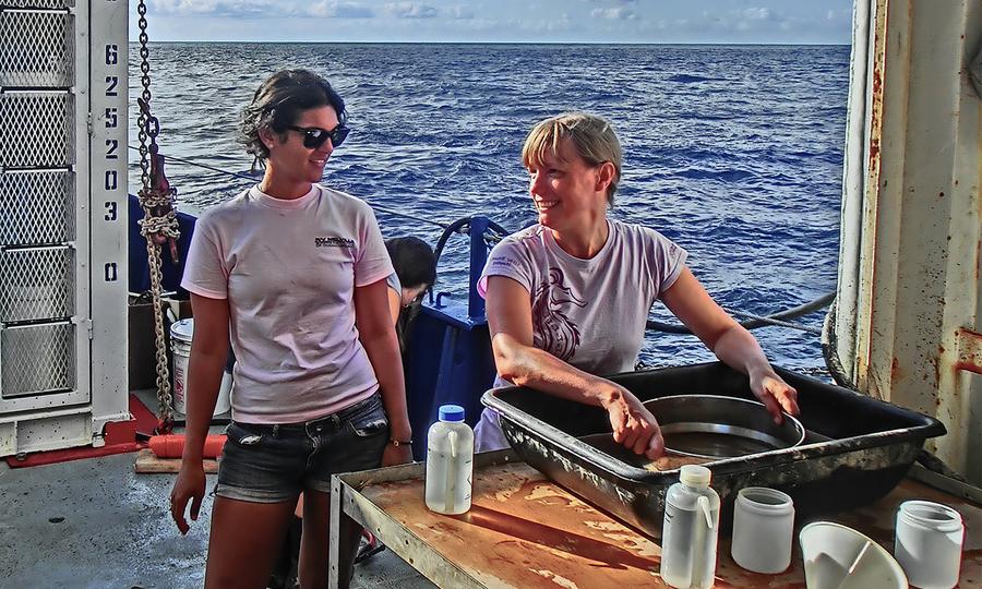 Två forskare ombord på ett fartyg med öppen havshorisont i bakgrunden.