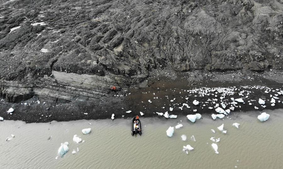 Drönarfoto av kustremsa med stenar och små snöklumpar 