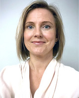 Minna Johansson, axellångt mörkblont hår, i vit blus.