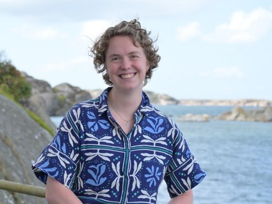 A woman is standing by the ocean. 