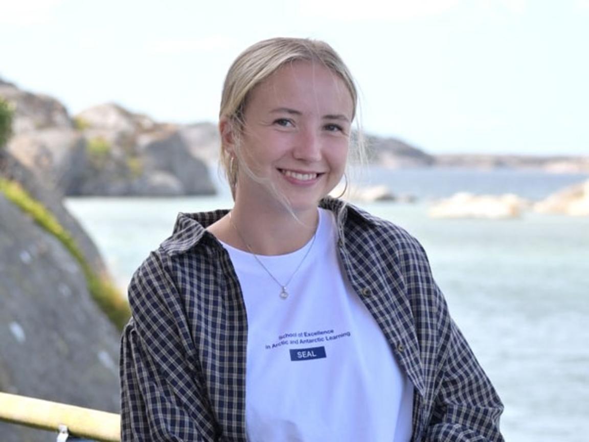 En kvinna står på en brygga framför vacker utsikt över havet. 