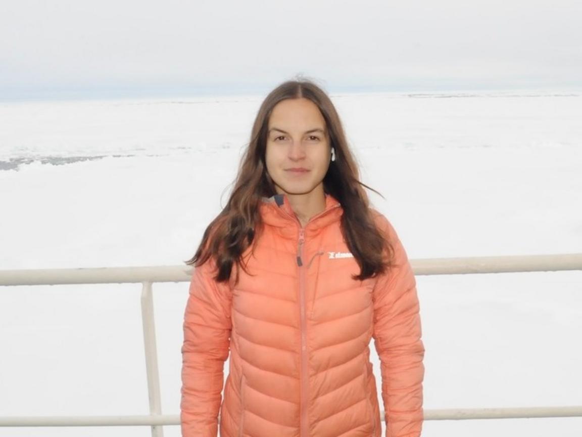 A woman is standing by the ocean. 
